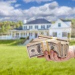 Handing Over Cash For House in Front of Beautiful New Home.